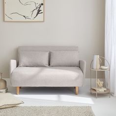 a white couch sitting next to a window in a living room on top of a rug