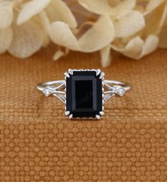 a black diamond ring sitting on top of a wooden table next to some white flowers