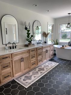 a large bathroom with double sinks, mirrors and bathtub in the middle of it