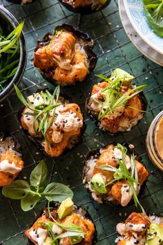 small appetizers are arranged on a wire rack with sauces and greens around them