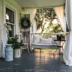 a porch covered in white furniture and curtains