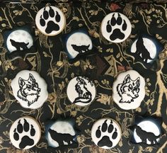 decorated cookies in the shape of wolf paws on a black and gold tablecloth with leaves