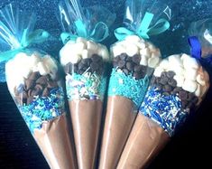 four cones with chocolate and marshmallows on them are wrapped in cellophane