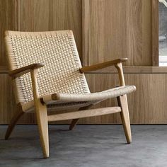 a wooden chair sitting in front of a wall with wood paneling on the walls