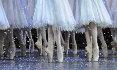 several ballerinas are lined up in white tutu skirts and ballet shoes with snow falling on them