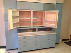 an old fashioned kitchen with blue cabinets and white counter tops, is shown in this image