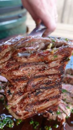 someone is cutting up some steak on a plate with sauce and parsley around it