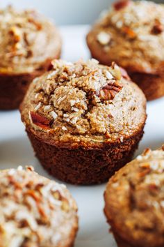 several muffins on a white plate with pecans in the middle and other toppings