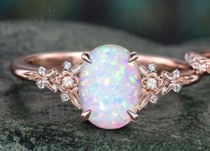 an opal and diamond ring sitting on top of a rock