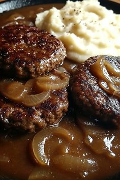 two hamburger patties, mashed potatoes and gravy in a skillet