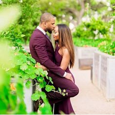 an engaged couple cuddles in the garden at their engagement photo shoot on a bridge