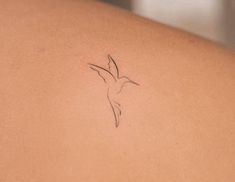 the back of a woman's shoulder with a small bird tattoo on her left arm