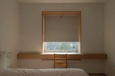 a bed sitting under a window next to a wooden desk