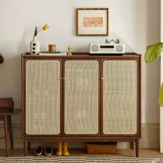 an old radio sits on top of a cabinet next to a potted plant in a living room