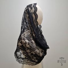 a mannequin wearing a black lace shawl on top of a white headdress