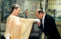 a man in a tuxedo standing next to a woman wearing a dress and tiara