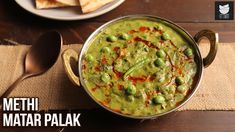 a metal pan filled with green peas next to tortilla chips on top of a wooden table