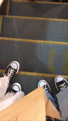 two people standing on an escalator with their feet up