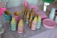 ice cream cones are lined up on a table with pink and blue decorations around them