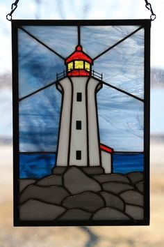 a stained glass window with a light house on it's side and water in the background