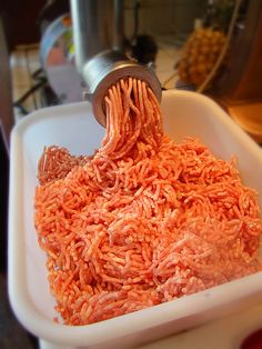 someone is grating red rice in a white bowl on the kitchen counter with an electric blender