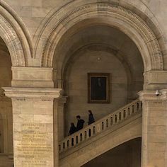 people are walking up and down the stairs in an old building with stone pillars, arches and arched doorways