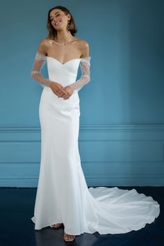 a woman wearing a white wedding dress with long sleeves and an off the shoulder top