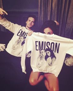 a man and woman holding up shirts that say emosn on them while standing next to each other