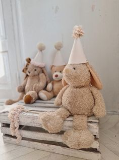 three stuffed animals sitting on top of a wooden crate in front of a white wall