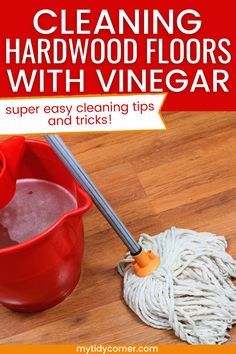 a red bucket and mop on the floor with text that reads cleaning hardwood floors with vinegar