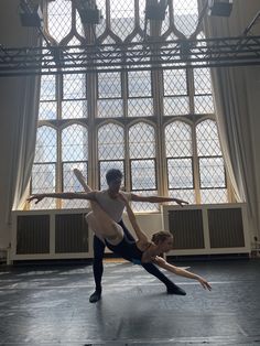 a man and a woman are doing ballet in front of a large stained glass window