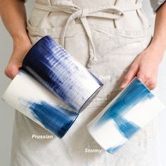 a person holding two cups in their hands and one is painted blue with white stripes