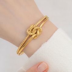 "Title: Knot Cuff Bracelet Product Description: Materials: High Quality Stainless Steel Finish: 18k Gold plated Size Specs: * The dimensions of the bracelet is apx. 6.5\", it can comfortably fit wrists ranging from 5\" to 7\". How To Order:   1- Explore our Collection   2- Select Your Favorites: Once you've found your favorite pieces, click on the product to view detailed information. Select your preferred options, such as metal /material type, gemstone, size, chain type , chain length etc.    3- Add to Cart: Hit the \"Add to Cart\" button to secure your chosen items. You can continue shopping or proceed to checkout when you're ready.   4- Review Your Order: Double-check your order in the shopping cart to ensure you have the right items and specifications. Make any necessary adjustments be Metal Bangle For Promise, Metal Bangle For Promise Occasion, Adjustable Bangle Bracelet For Promise, Gold Bangle Bracelets For Promise, Adjustable Dainty Gold Plated Bangle, Dainty Adjustable Cuff Bracelet For Anniversary, Adjustable Tarnish-resistant Cuff Bracelet For Anniversary, Adjustable Jubilee Bracelet Bangle For Anniversary, Gold Tarnish Resistant Bracelets For Promise