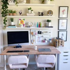 a desk with two chairs and a computer on top of it in front of a white wall