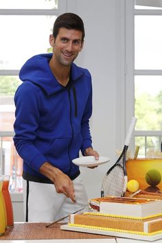 a man is cutting into a cake with a tennis racquet on the plate