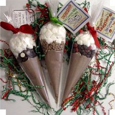 three cones filled with white chocolate and marshmallows on top of christmas decorations