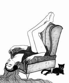 a woman laying on top of a chair next to a black cat