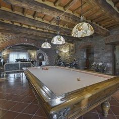 a pool table is in the middle of a large room with stone walls and ceilings