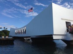 people are standing on the side of a bridge over water with an american flag flying in the background