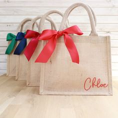 three bags with red, blue, and green ribbons tied to them on a wooden table