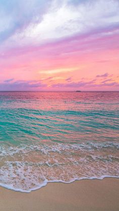 an ocean beach with waves coming in to shore and the sun setting over the water