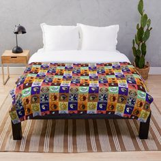 a bed with a colorful blanket on top of it next to a potted plant