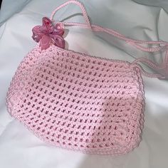 a pink crocheted purse with a flower on it