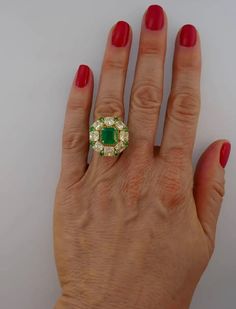 For Sale on 1stdibs - Sparkly and colorful cocktail ring that is a great addition to your jewelry collection. It is made of 18 karat (stamped) yellow gold and features a gorgeous Luxury Green Cluster Ring With Center Stone, Luxury Green Cluster Ring For Anniversary, Luxury Green Cluster Ring For Formal Occasions, Luxury Green Cluster Ring For Formal Events, Luxury Green Cluster Ring With Halo Setting, Luxury Green Cluster Ring With Round Cut, Luxury Hallmarked Green Diamond Ring, Luxury Green Hallmarked Diamond Ring, Luxury Yellow Rings For Collectors