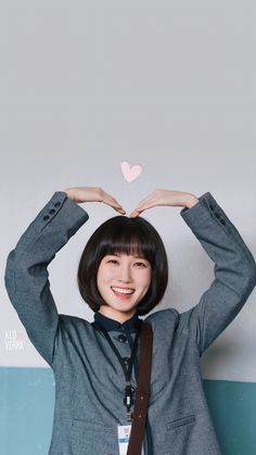 a young woman holding her hands up to her head with a heart above her head