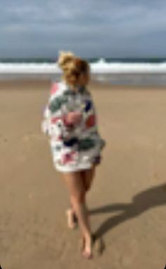 a woman walking on the beach with a frisbee in her hand