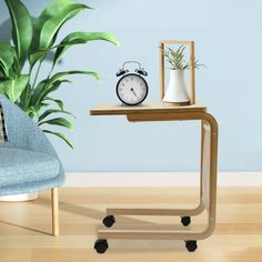 a small table with a clock on it next to a chair and potted plant