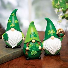 three green gnomes sitting next to each other on a table