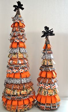 two orange and black christmas trees made out of ribbon, with bows on each tree