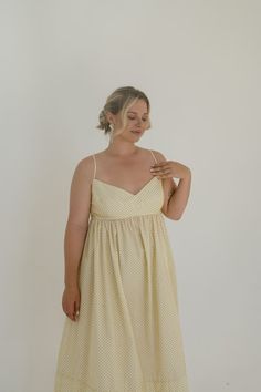 a woman in a yellow dress is posing for the camera with her hand on her hip